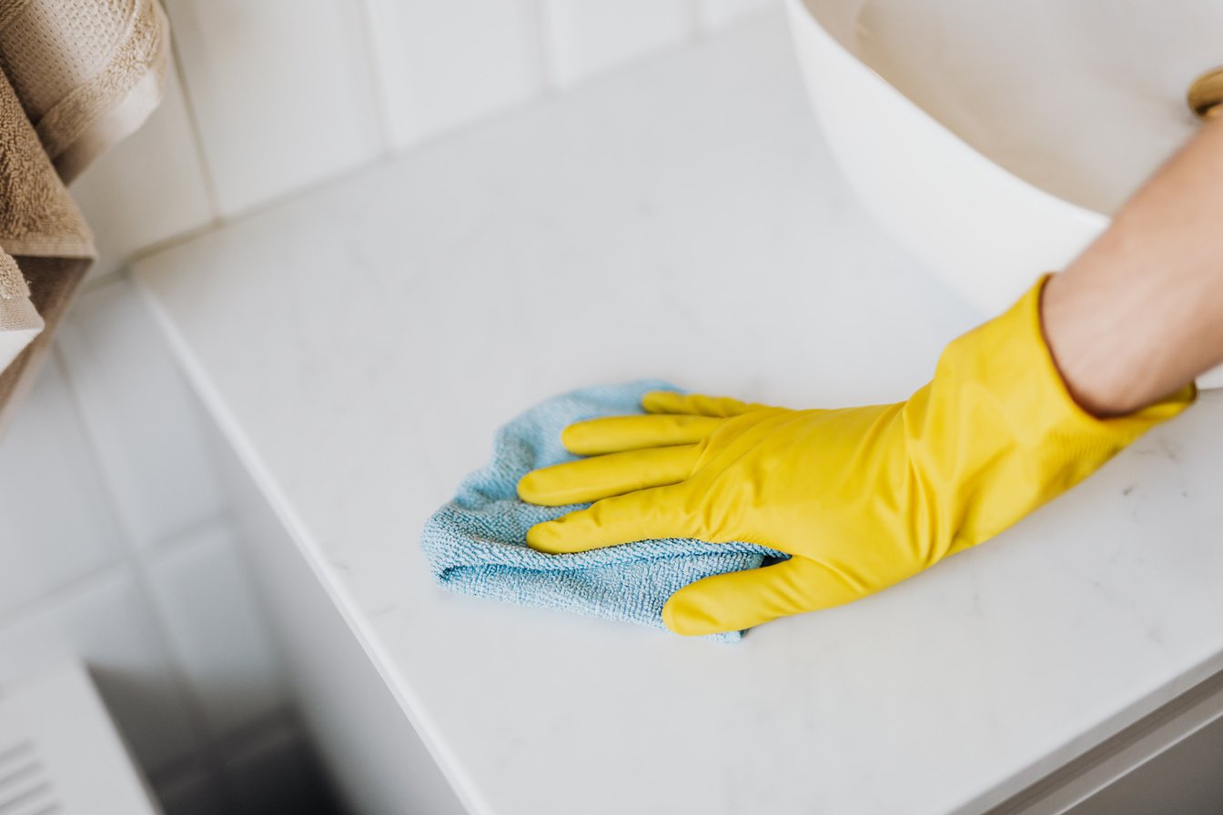 Crop person cleaning tabletop in bathroom